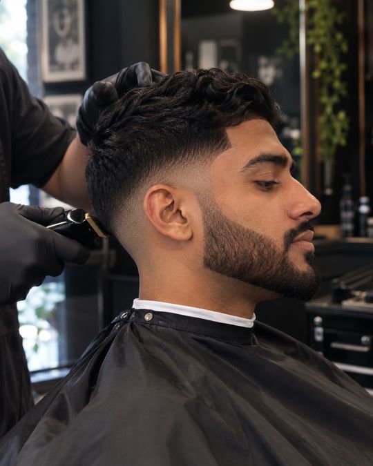A barber blending a taper fade with clippers